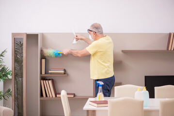 Fototapeta premium Old man doing housework at home