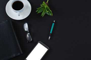 Black coffee, flora, pen, spectacles, mobile phone and organizer on black background