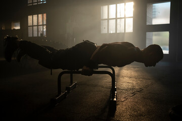 Strong bodybuilder man doing calisthenics planche workout on parallel bars