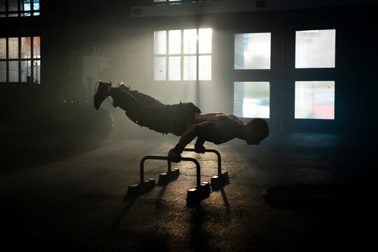 Man doing exercise calisthenics, bent arm straddle planche in gym