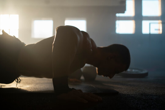 Athlete doing push ups and working out exercising core and arms on the floor of fitness center