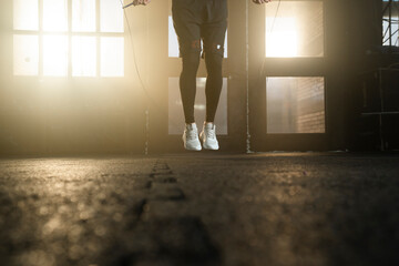 Close-up shot on legs, handsome man doing skipping rope workout wearing casual shoes at gym