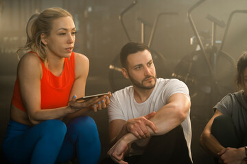 Young friends sitting together, having a discussion after exercising together in the gym