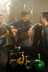 Friends on the gym floor after training, exercise motivation and relaxing after cardio. Laughing, happy people with a group discussion about workout