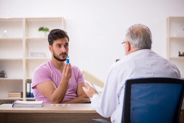 Obraz premium Young male patient visiting old male doctor