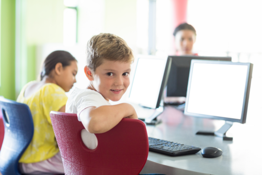 Smiling boy using computer - Powered by Adobe