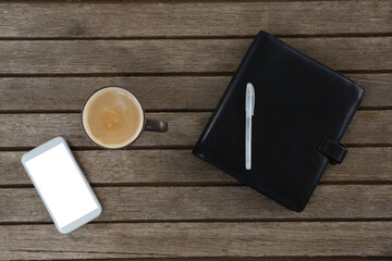 Mobile phone, coffee, pen and organizer on wooden plank