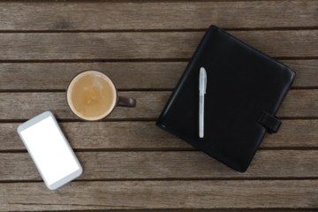 Mobile phone, coffee, pen and organizer on wooden plank
