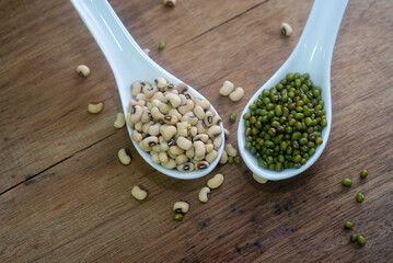 Natural grains, consisted of green bean, and soybean seeds in spoon on vintage style wooden background.