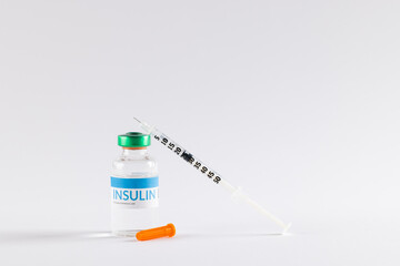Insulin in vial and uncapped syringe on white background with copy space