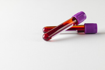 Fototapeta na wymiar Two blood sample tubes with purple lids, on white background with copy space