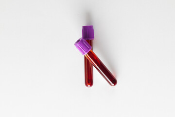 Two blood sample tubes with purple lids, on white background
