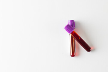 Two blood sample tubes with purple lids, on white background with copy space