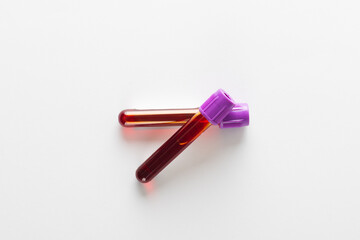 Two blood sample tubes with purple lids, on white background