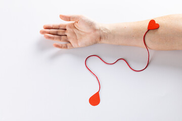 Arm of caucasian woman with heart and red string with blood drop, on white background