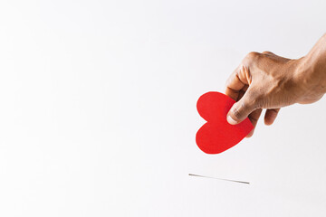 Hand of biracial man red heart into slot, on white background with copy space