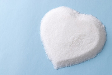 Fototapeta na wymiar Sugar in heart shape on blue background
