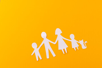 White paper cut out of family with two children and ca and copy space on orange background