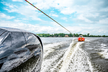 Inflatable raft being pulled at a high speed by a boat in a recreational activity called tubing