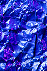 Close up of crumpled and shiny blue foil with copy space