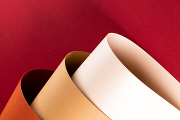 Close up of orange, beige and white paper on red background with copy space