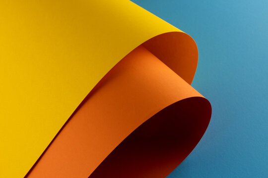 Close up of yellow and orange paper on blue background with copy space