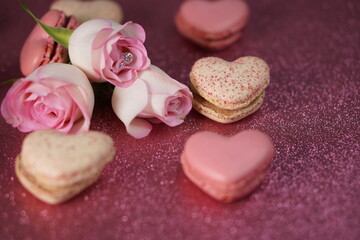 Heart-shaped macarons with roses on glittery pink background, Valentines day