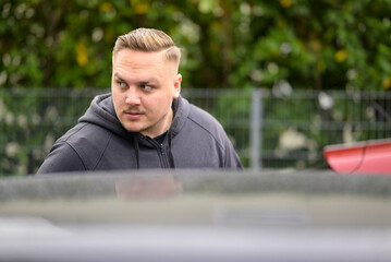 Young man standing beside a car