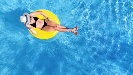 Fototapeta na wymiar Beautiful woman in hat in swimming pool aerial drone view from above, young girl in bikini relaxes and swims on inflatable ring donut and has fun in water on tropical vacation on holiday resort 
