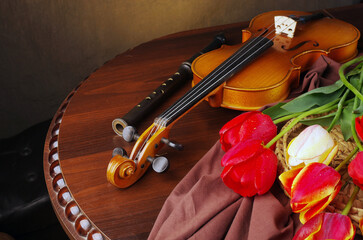 Violin, pipe, a bouquet of tulips and daffodils on a wooden table.