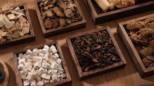 A closeup view of many types of herbs, placed on wooden tray with square and rectangle shape. Traditional chinese medicine concept