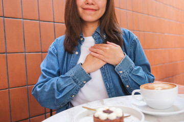 Closeup image of a woman putting hands on her chest in cafe