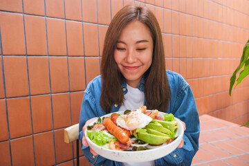 Portrait image of a young woman holding and eating salad