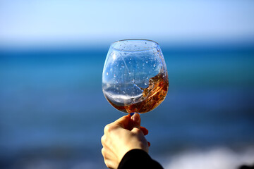 a glass of port wine on the background of the sea, a hand with wine