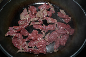 Beef pieces with salt and pepper frying in a pan with oil