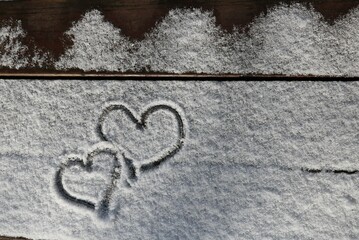 Zwei Herzen gemalt in den Schnee auf einer verschneiten Bank