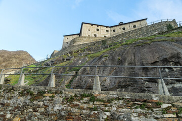 Fototapeta na wymiar Bard, Italy. View from below of the Forte di Bard, an ancient military fortress located at the entrance to the Aosta Valley, a few kilometers from the border with Piedmont. 2023-03-25.