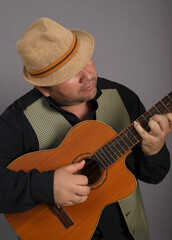 Studio portrait of man wearing a hat playing an old Cuban tres.