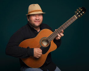 Studio portrait of man wearing hat and playing guitar