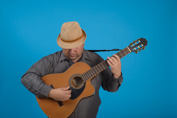Fototapeta na wymiar Studio portrait of man wearing hat and playing guitar