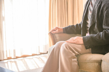 ソファに座って外を眺める高齢の女性