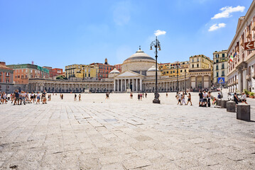 Naples, Italy. View on a sunny day of Piazza Plebiscito with some tourists walking across the square. In the background the Royal Pontifical Basilica of San Francesco da Paola. 2022-08-20.