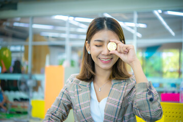 Beautiful asian business woman hold a coin in her one hand and covered on her eye  while close her eyes with a smile on her face.