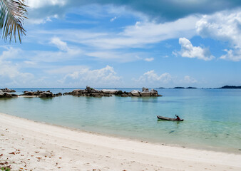 Fototapeta na wymiar Beach with boat, white sand and big rocks.