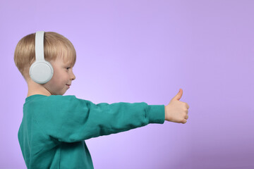 boy child enjoying music in headphones, thumbs up