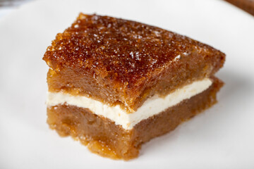 Bread pudding on wood floor. Traditional Ramadan dessert. Bread kadayif with cream in the middle. Local name kaymaklı ekmek kadayifi. Close up