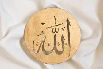 Fotobehang Allah bismillah names close up. Golden wooden calligraphy of islamic god. on white textile, top view. © Irina