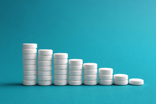 On a turquoise background, round medicine pills stand in the form of a ladder.