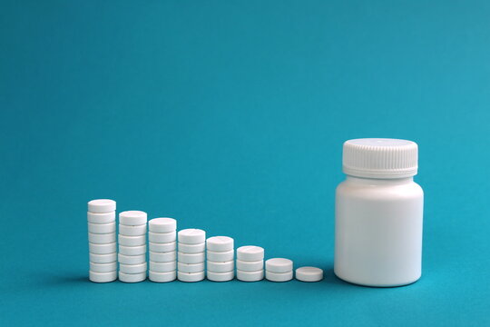  On a turquoise background, round medicine pills stand in the form of a ladder.	