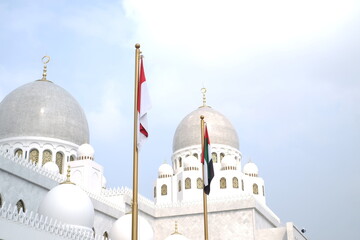 Indonesian and UAE flags with mosque dome background